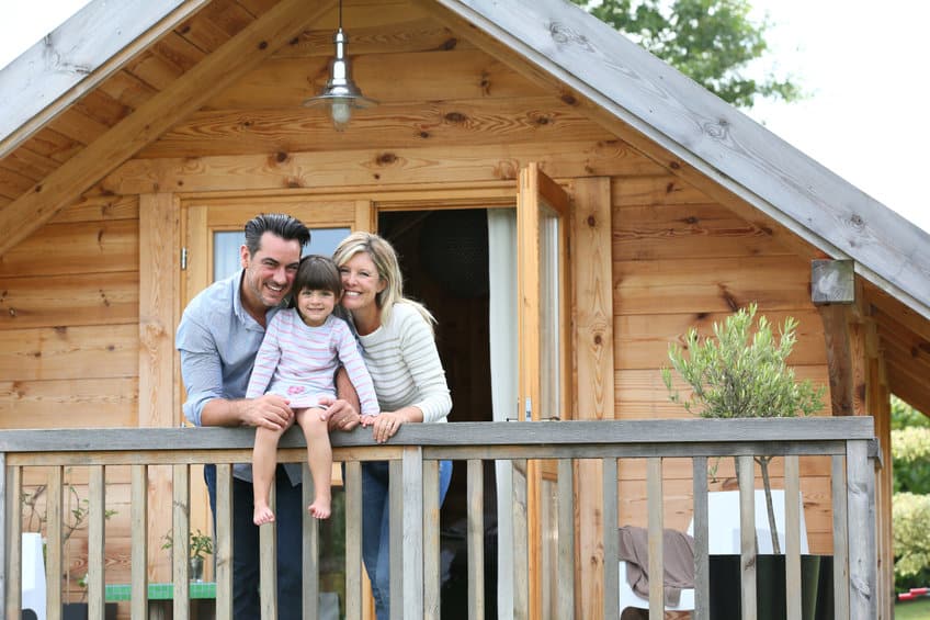 a couple holding their daughter on the balcony of their custom-built cabin in texas