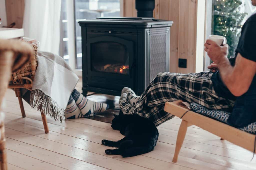 a couple and their cat sitting in front of their custom cabin's fireplace