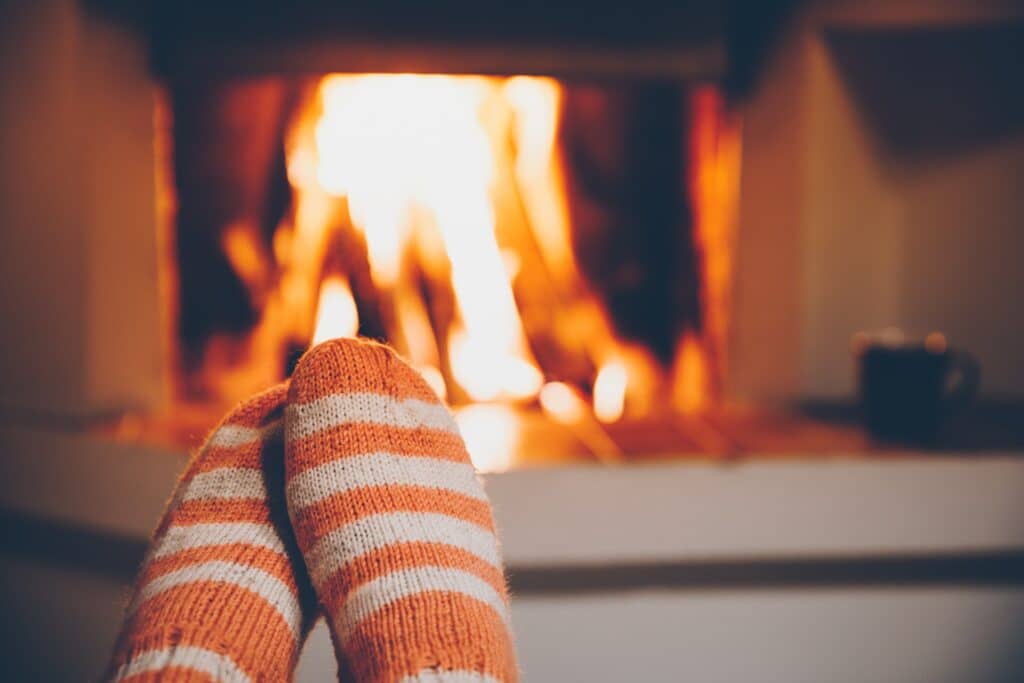 cabin owner wearing fluffy socks next to the fireplace in their cabin