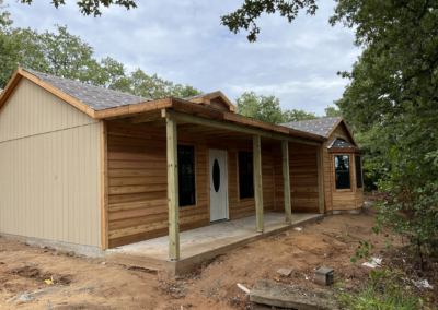 front exterior of a custom texas cabin built by ormeida with natural wood and unfinished roof