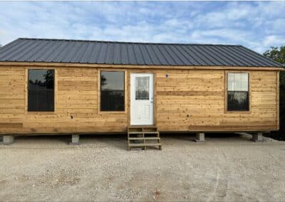 front exterior of a custom texas cabin built by ormeida with natural wood and dark metal roof