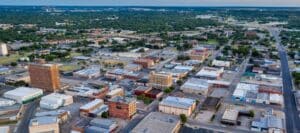 Aerial view of downtown Brownwood, Texas, with a mix of historic buildings and modern infrastructure surrounded by greenery