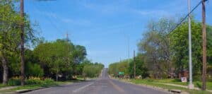 Tree-lined residential street in Coleman, Texas, with clear skies and utility poles lining the road